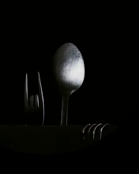 Cuchara y tenedor de plata sobre un fondo negro